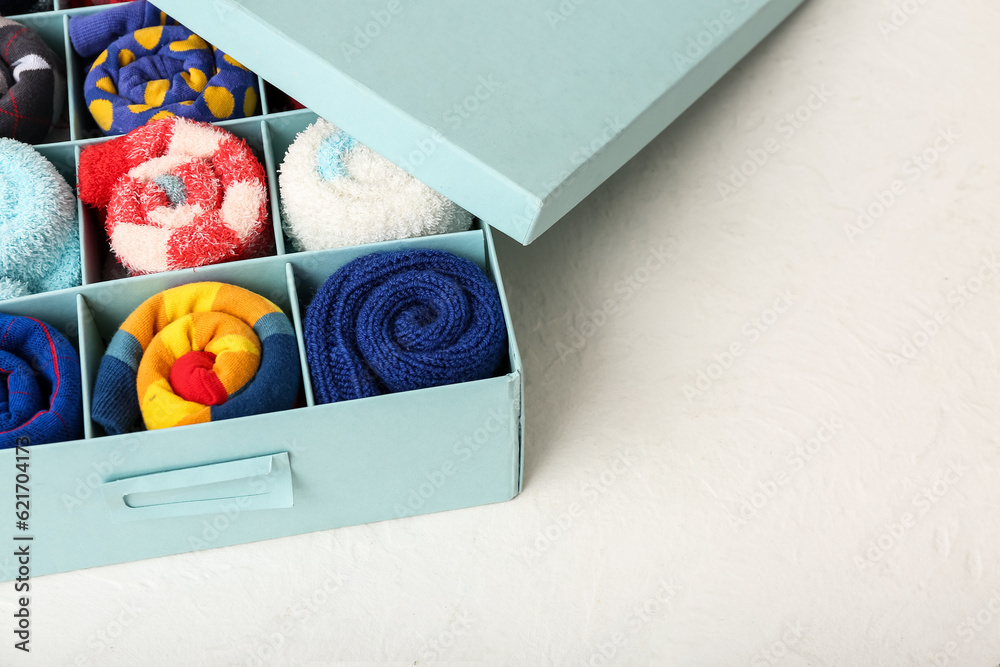 Box with different socks on light background, closeup