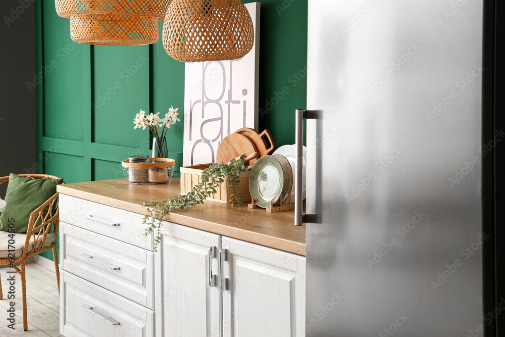 Interior of kitchen with stylish fridge, counters, lamps and chair