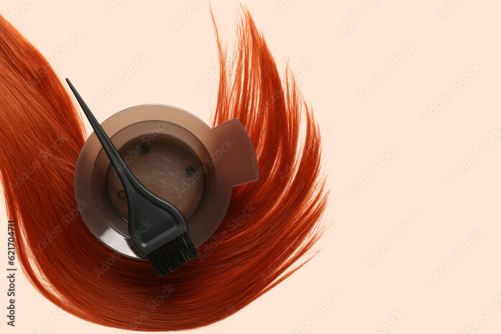 Ginger hair strand, bowl for hair dye and brush on color background, closeup