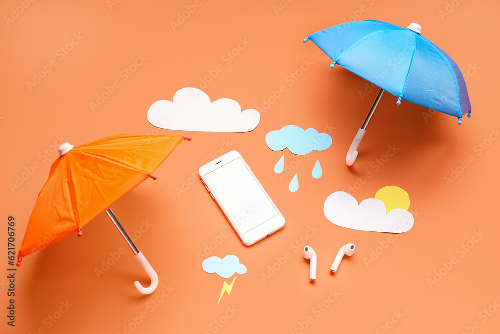 Mobile phone with paper clouds, rain drops, umbrellas and earphones on red background. Weather forec