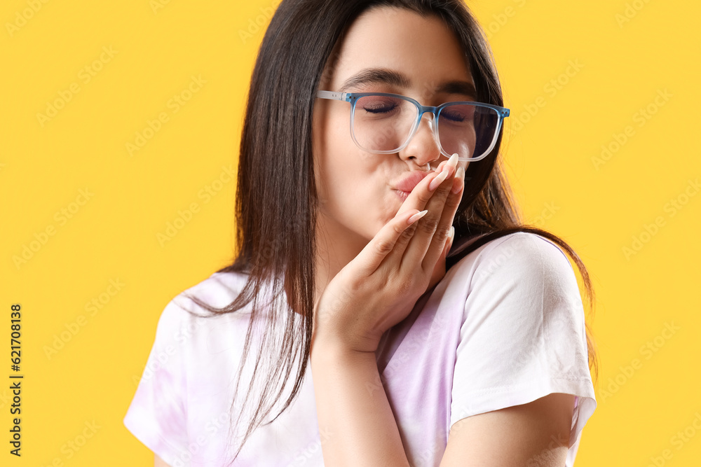 Pretty young woman wearing glasses on yellow background