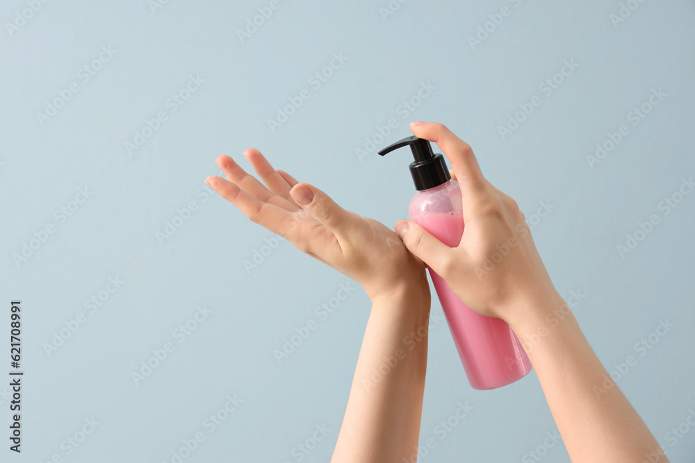 Hands with liquid soap on light blue background