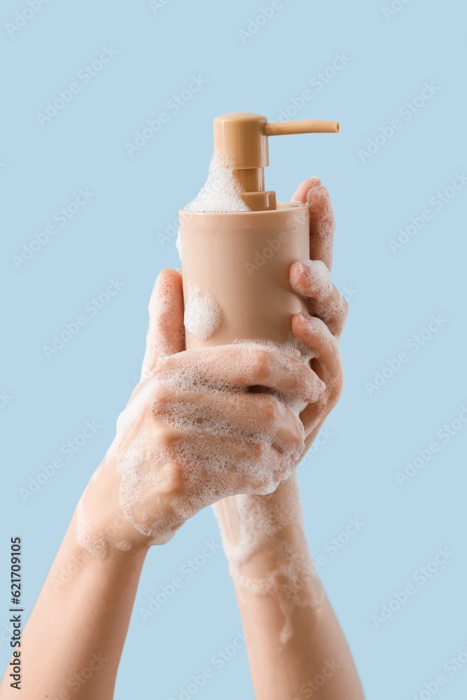 Hands with liquid soap on light blue background