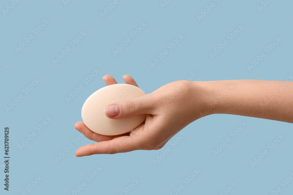 Hand with soap on light blue background