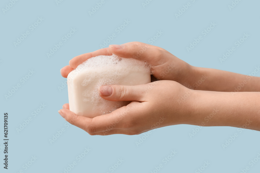 Hands with soap on light blue background