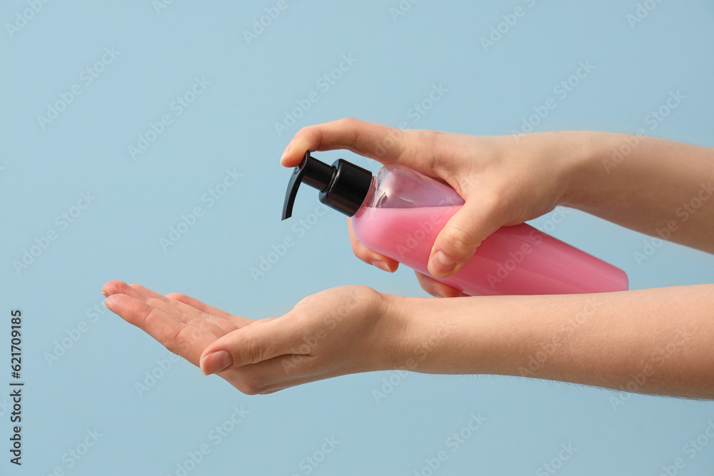 Hands with liquid soap on light blue background