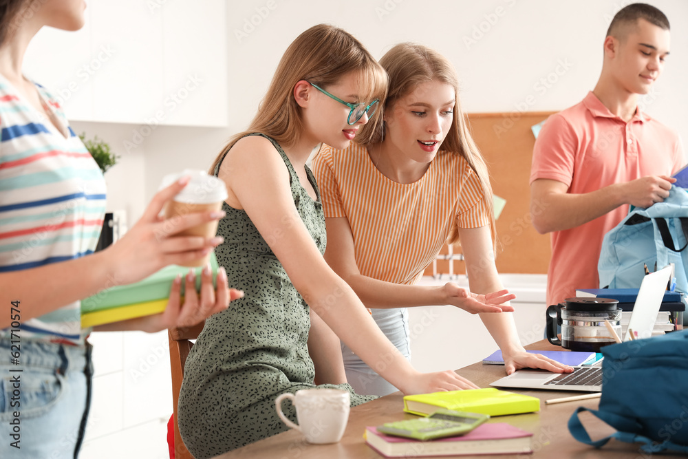 Group of students studying with laptop in kitchen