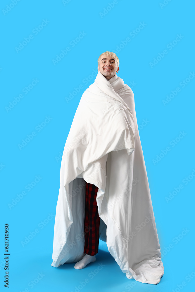 Young man with blanket on blue background