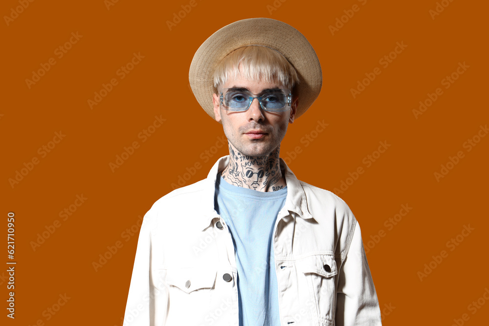 Young tattooed man in stylish sunglasses on color background