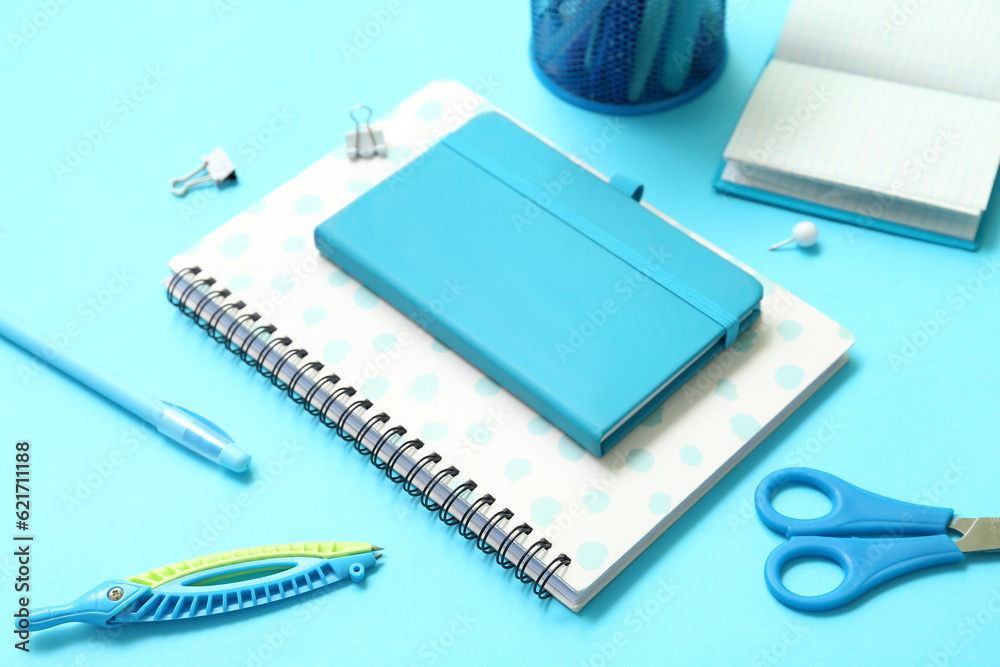 Notebooks with school stationery on blue background, closeup