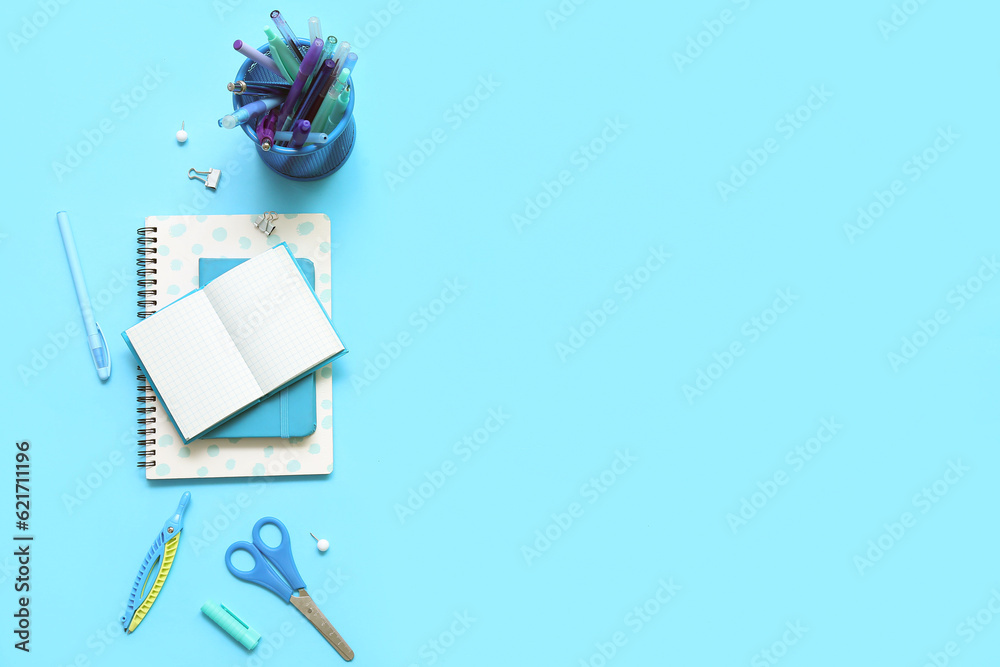 Composition with notebooks and different school stationery on blue background