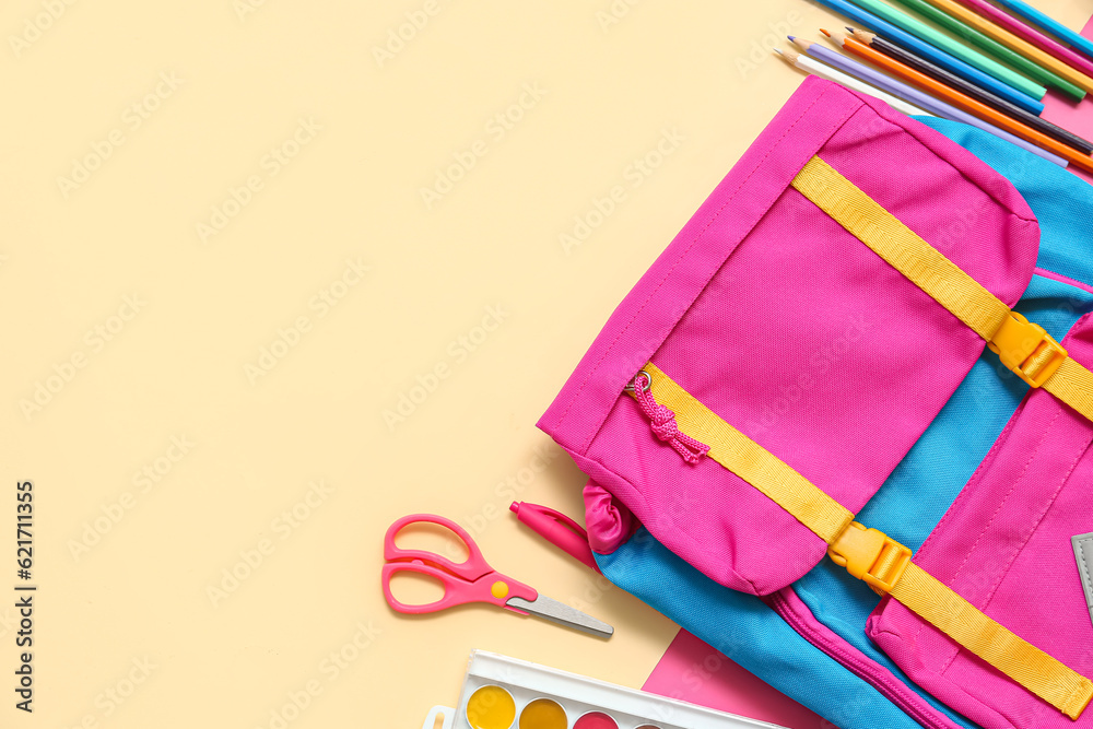 School backpack with pencils and paints on beige background