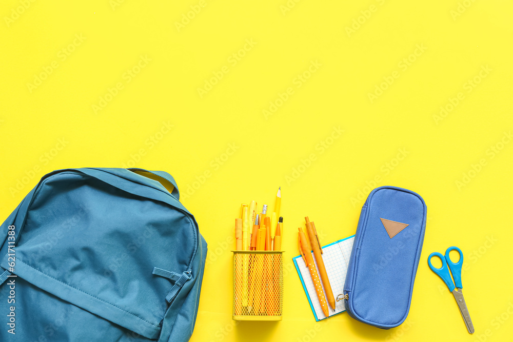 School backpack with stationery on yellow background