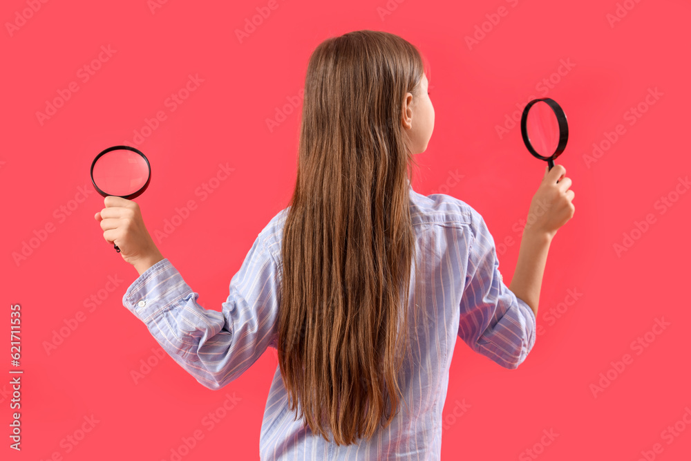 Little girl with magnifiers on red background, back view