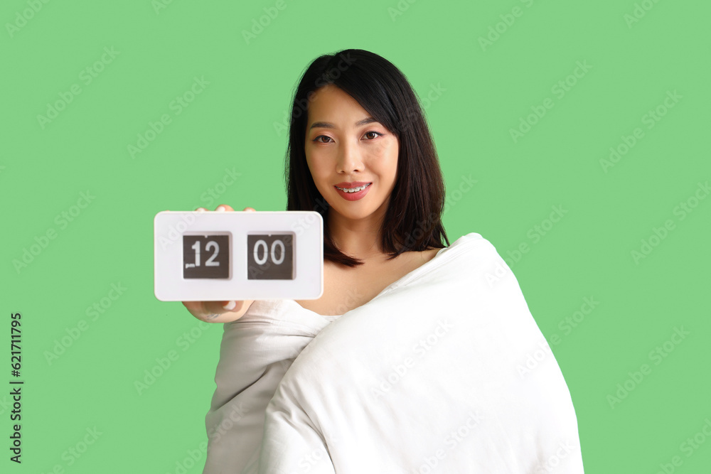 Beautiful Asian woman with blanket and clock on green background