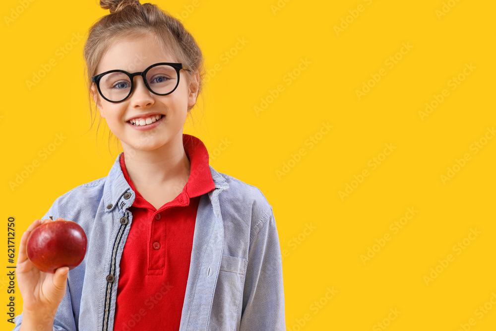 Little girl with apple on yellow background