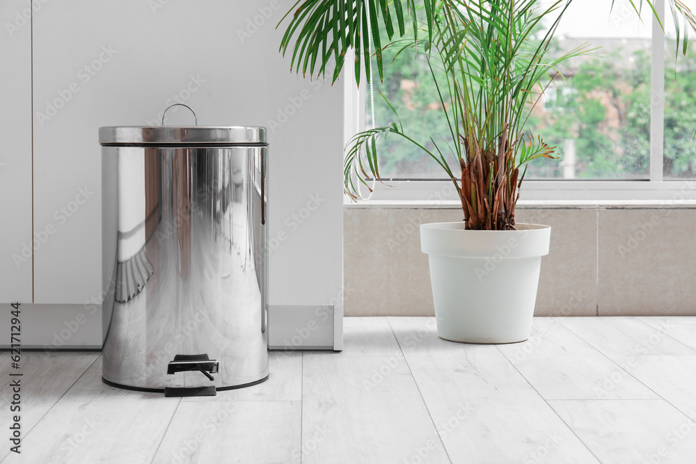 Metallic trash bin in interior of light kitchen