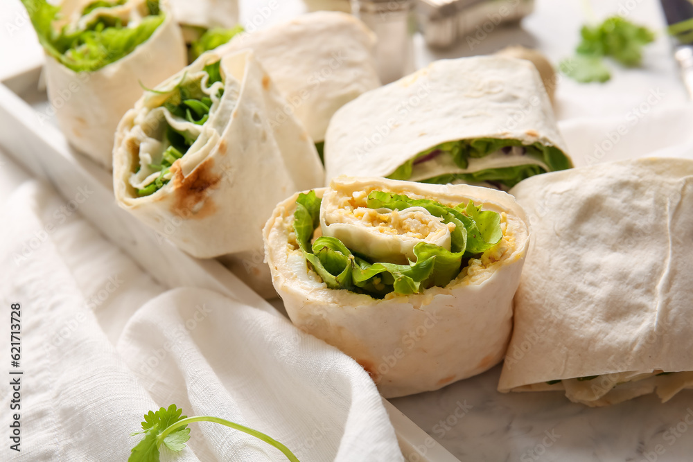 Plate of tasty lavash rolls with egg, onion and greens on table