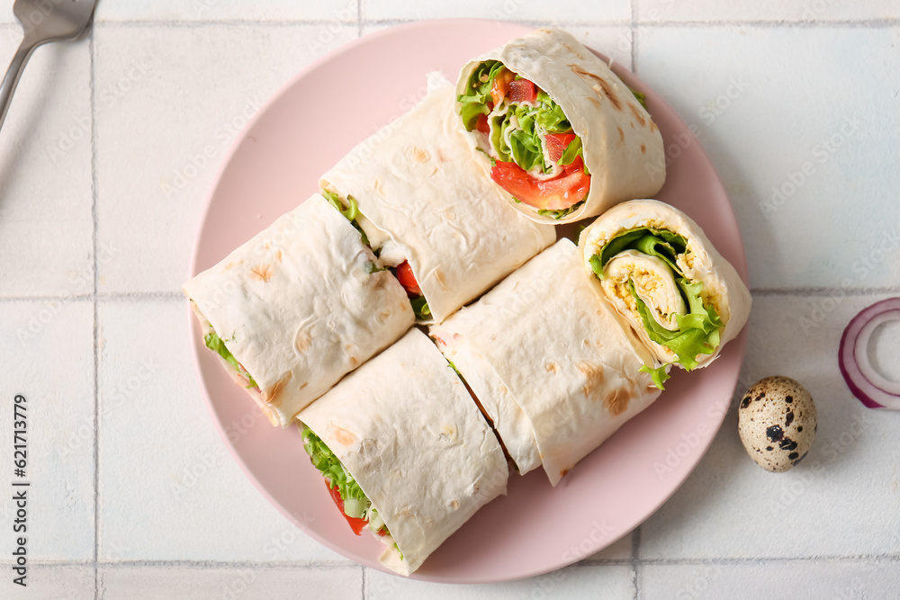 Plate of tasty lavash rolls with tomatoes, egg and greens on white tile background