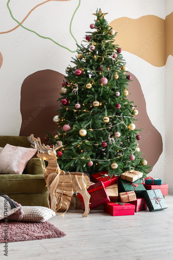 Interior of living room with Christmas tree, green sofa, gift boxes and decorations