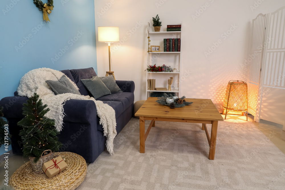 Interior of living room with sofa, coffee table, shelving unit and Christmas decorations