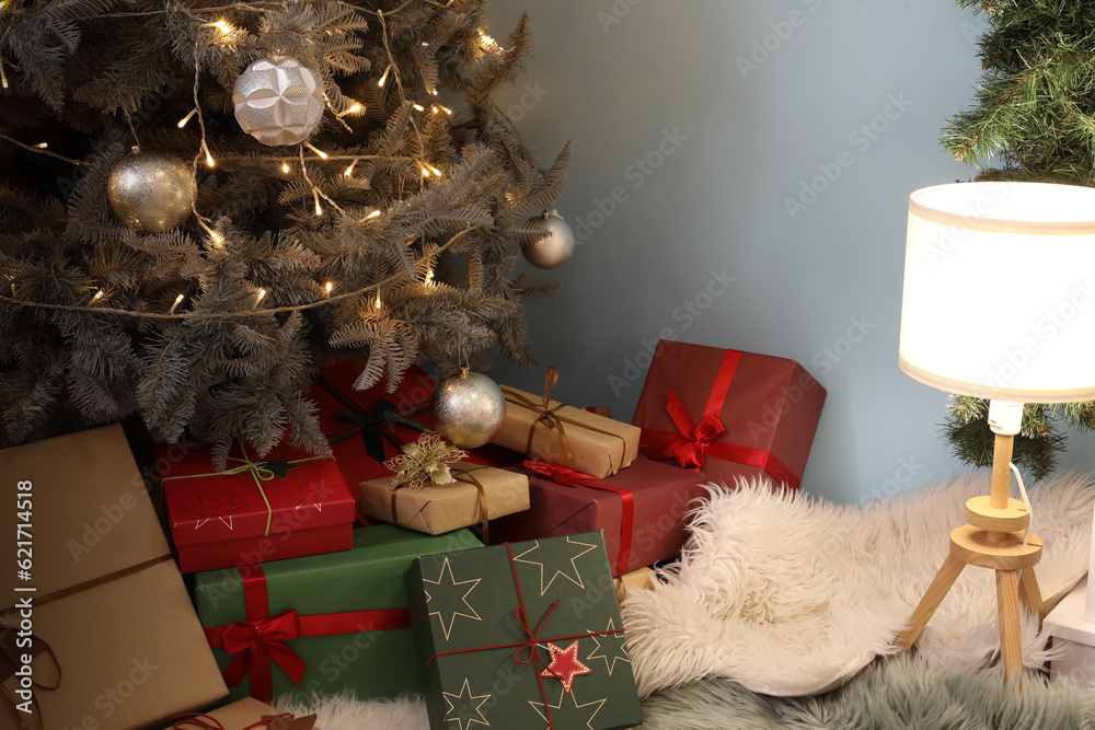 Interior of living room with Christmas tree, gift boxes and glowing lamp