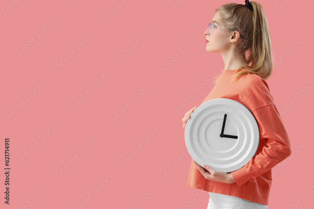 Young woman with clock on pink background. Deadline concept