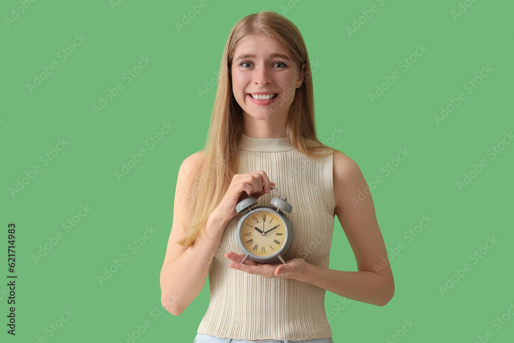 Young woman with alarm clock on green background. Deadline concept