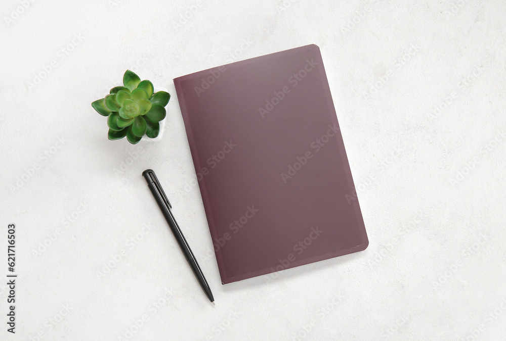 Brown notebook with pen and houseplant on white background