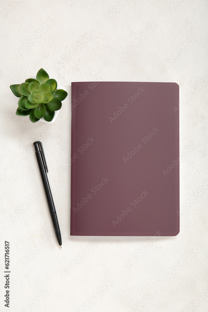 Brown notebook with pen and houseplant on white background