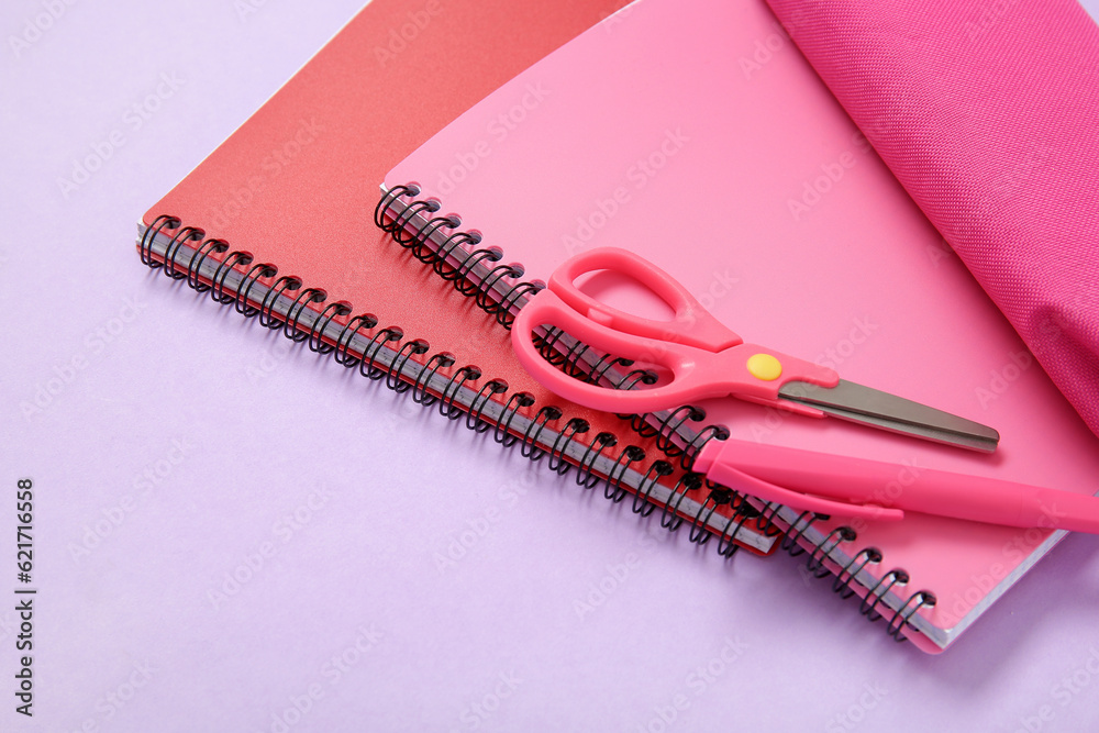 Notebook with pencil case and different stationery on lilac background