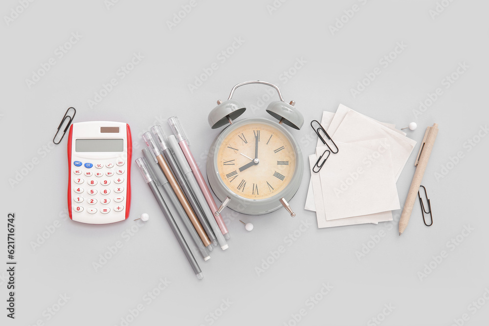 Alarm clock with calculator and different stationery on grey background