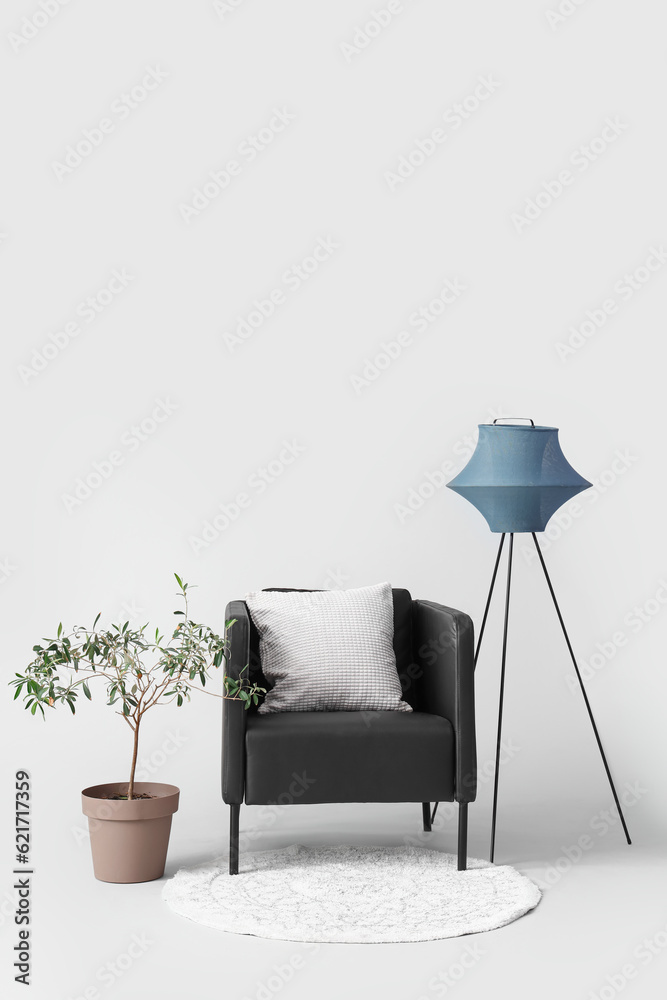 Black armchair with lamp and houseplant on white background