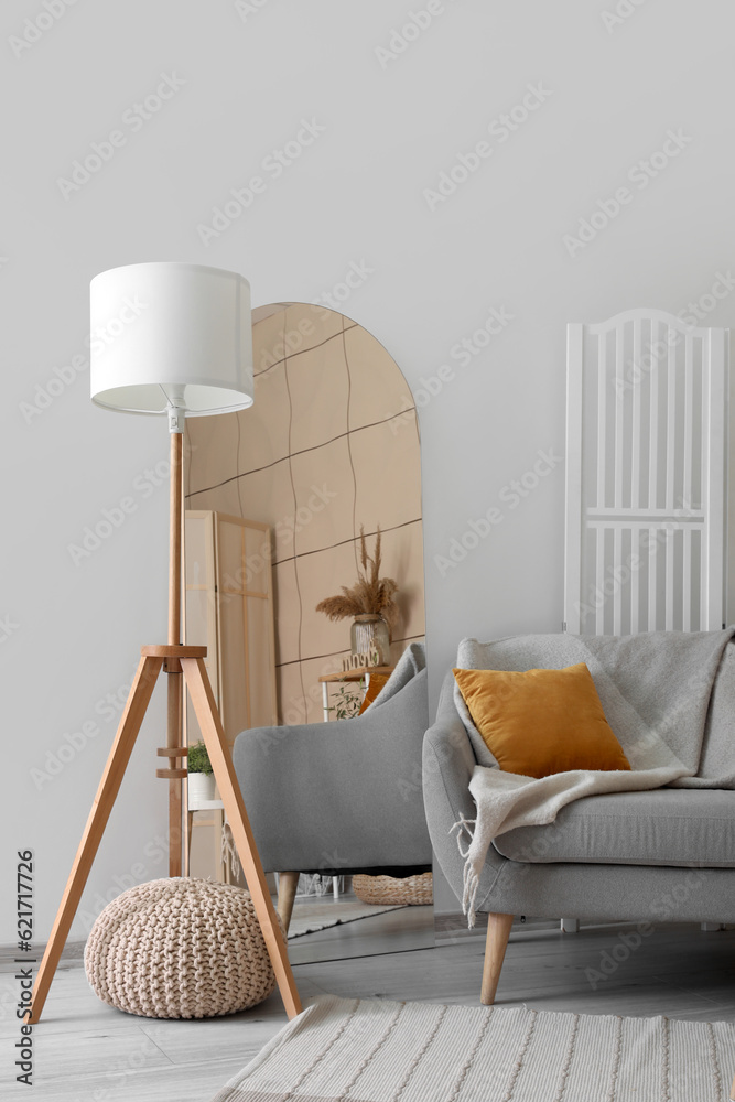 Interior of living room with grey sofa, mirror and lamp