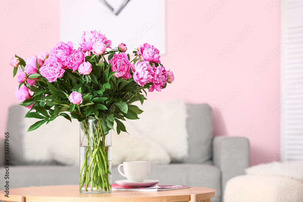 Vase of pink peonies on coffee table with couch in living room