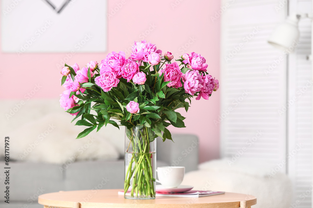 Vase of pink peonies on coffee table with couch in living room