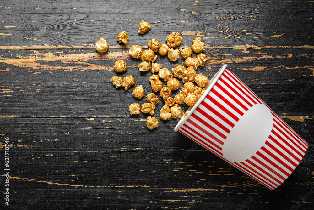 Bucket with tasty popcorn on black wooden background