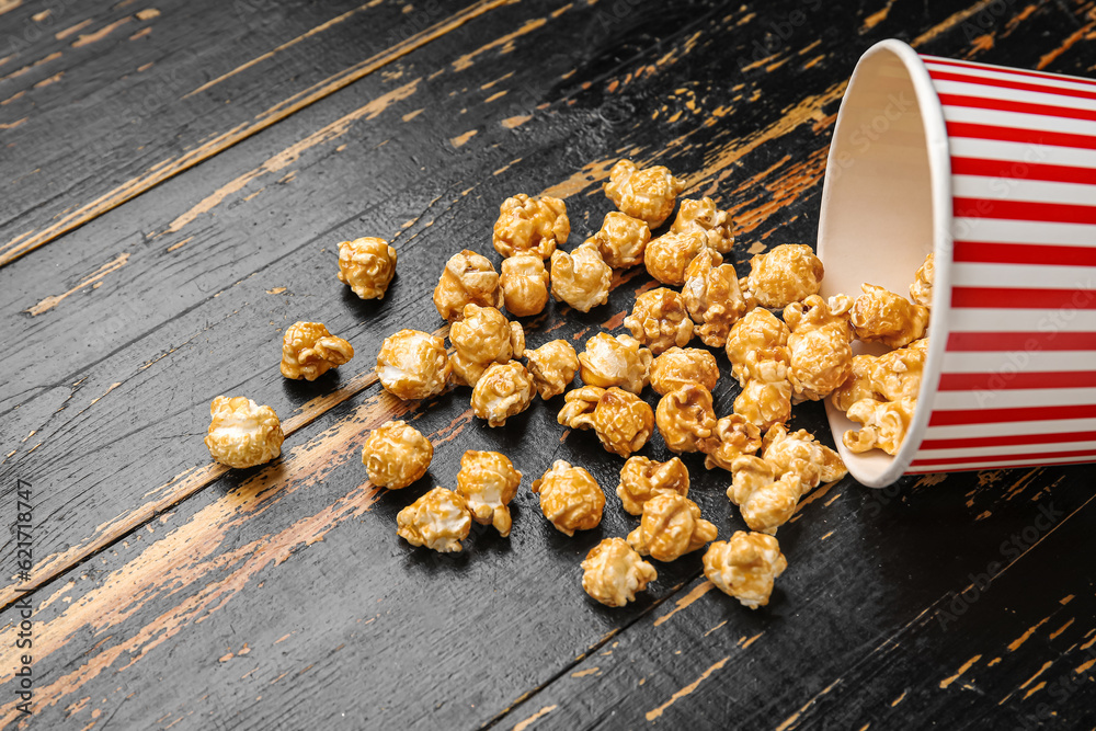 Bucket with tasty popcorn on black wooden background