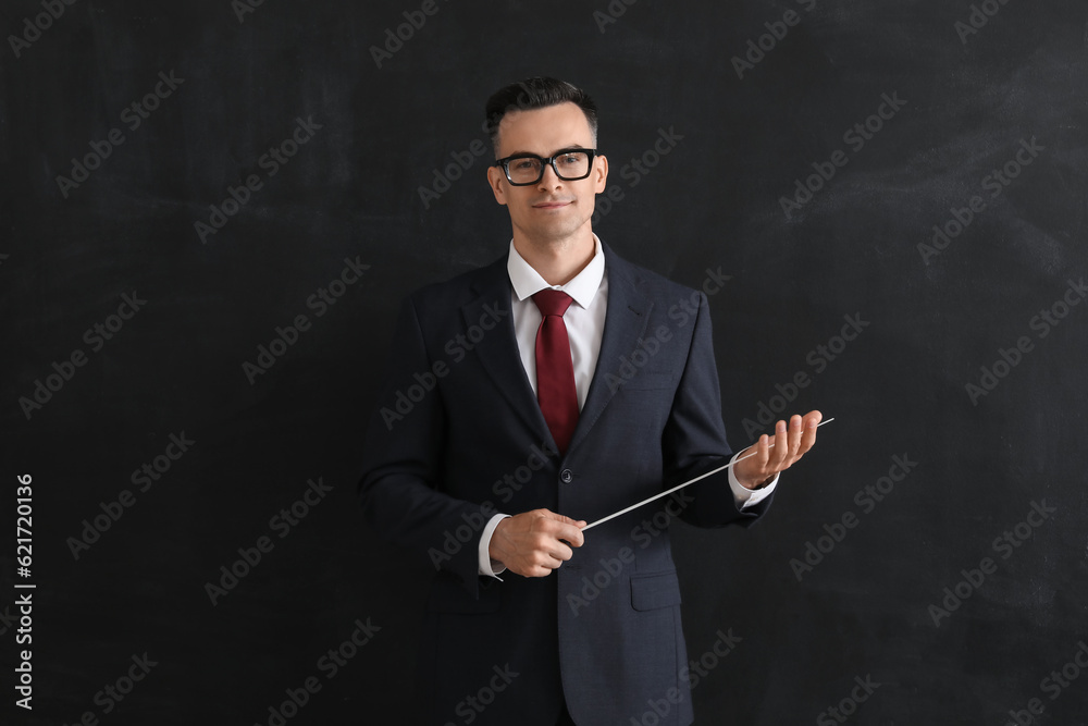 Male teacher with pointer near blackboard in classroom