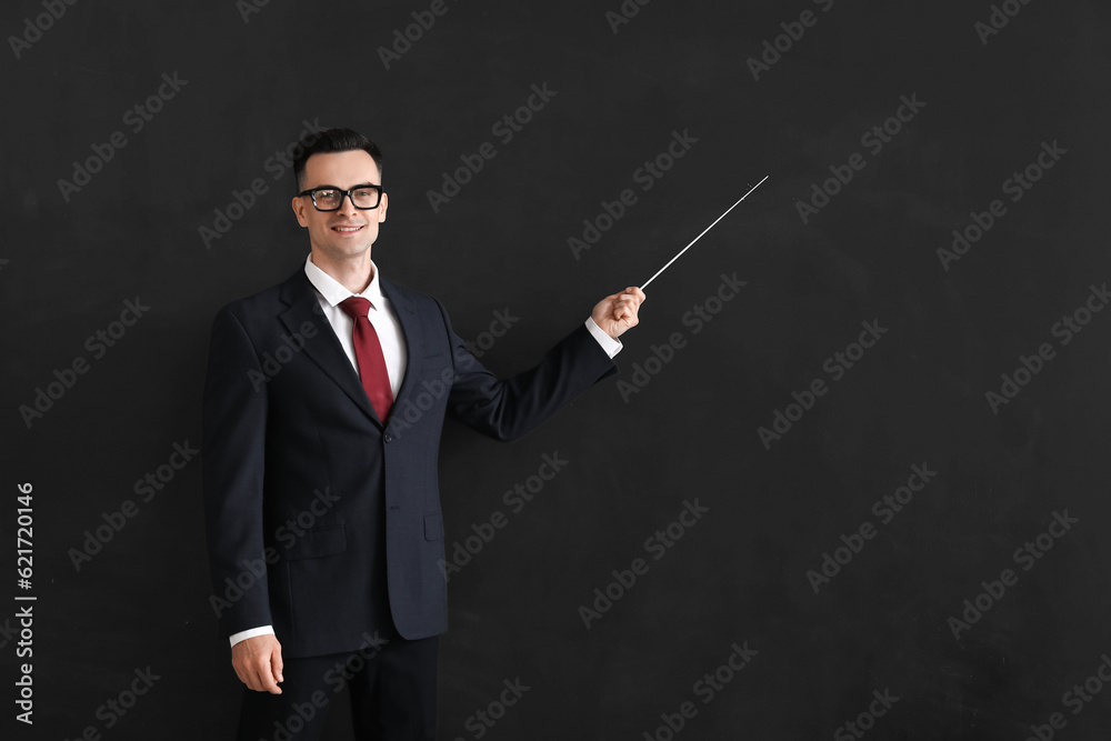 Male teacher with pointer near blackboard in classroom