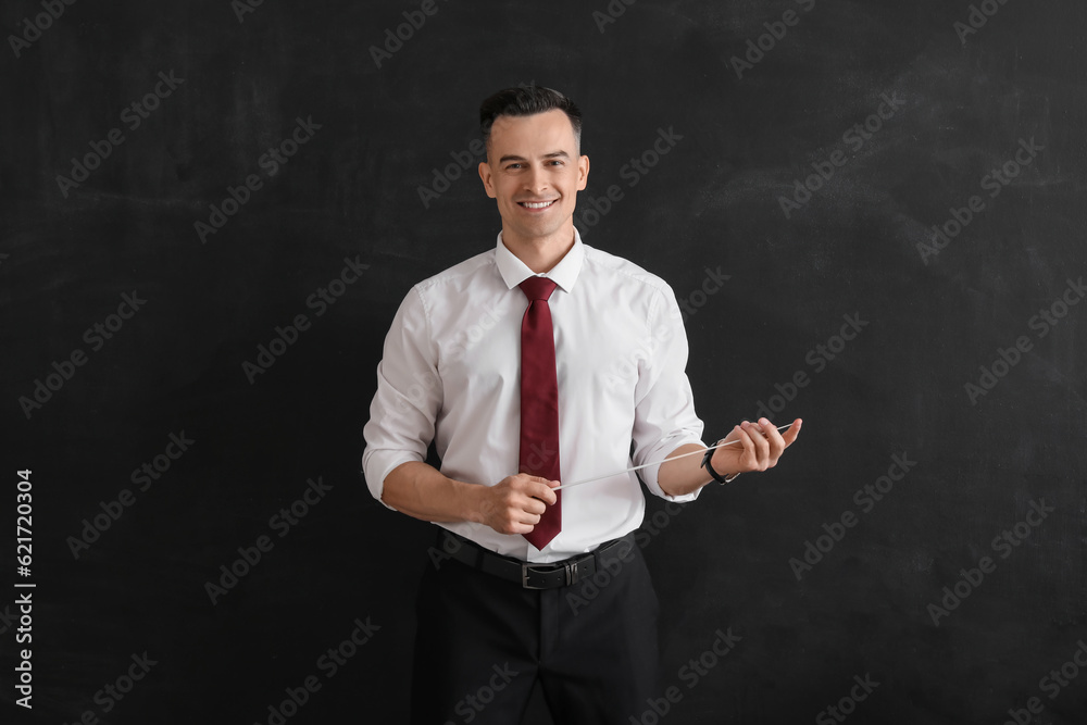 Male teacher with pointer near blackboard in classroom