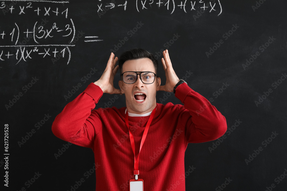 Stressed Math teacher near blackboard in classroom