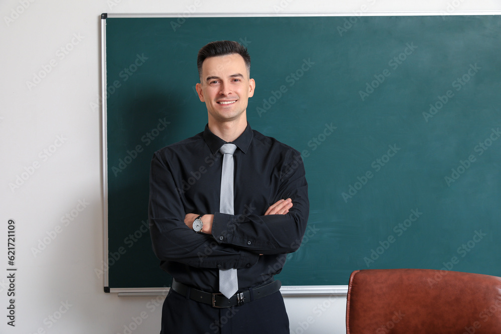 Male teacher near chalkboard in classroom