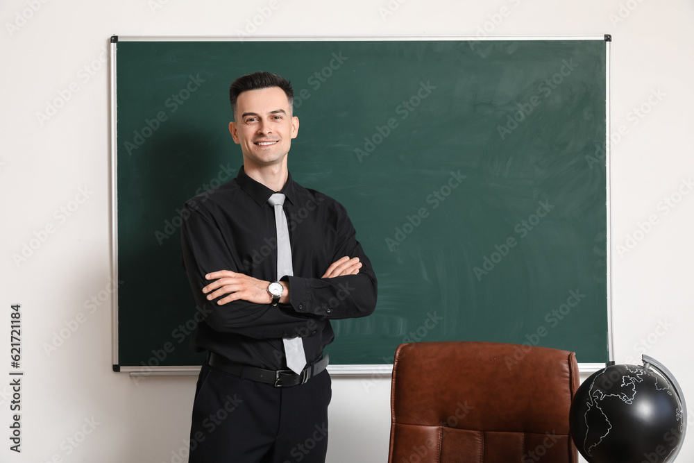 Male teacher near chalkboard in classroom