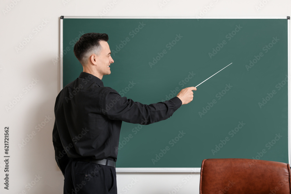 Male teacher with pointer near chalkboard in classroom