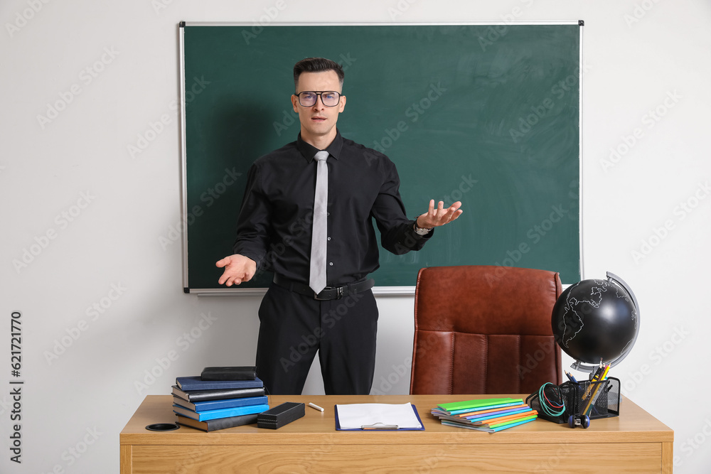 Male teacher conducting lesson near chalkboard in classroom