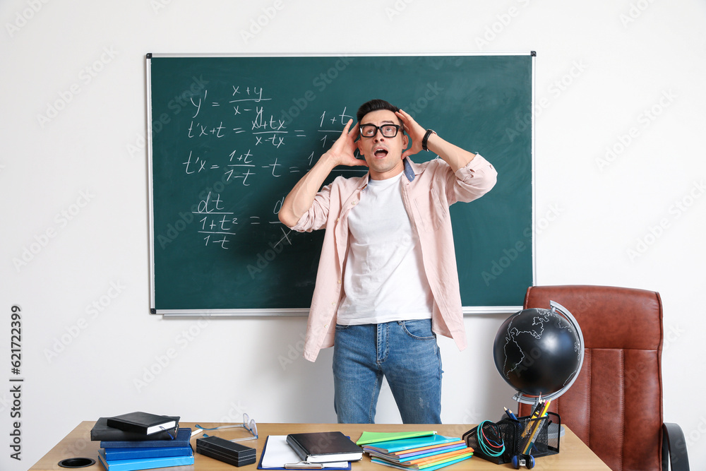 Shocked Math teacher near chalkboard in classroom