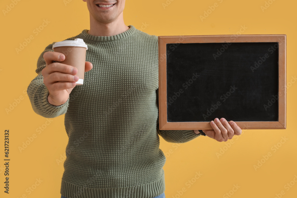 Male teacher with chalkboard and cup of coffee on yellow background, closeup