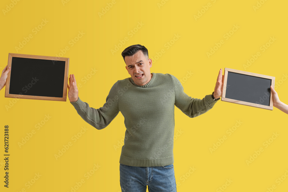 Stressed male teacher rejecting chalkboards on yellow background