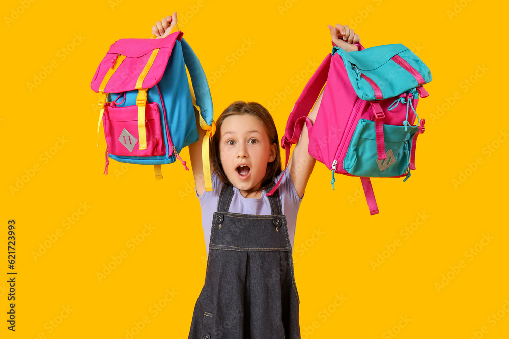 Little girl with backpacks on yellow background